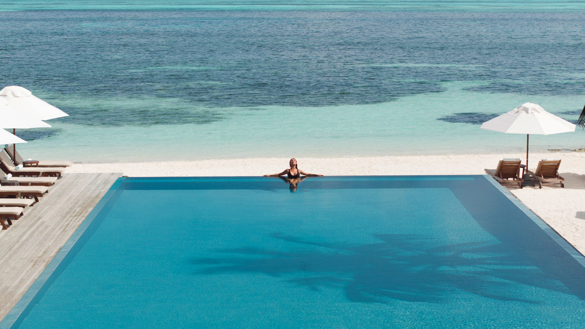 Aerial view of a woman in the pool at LUX* South Ari Atoll