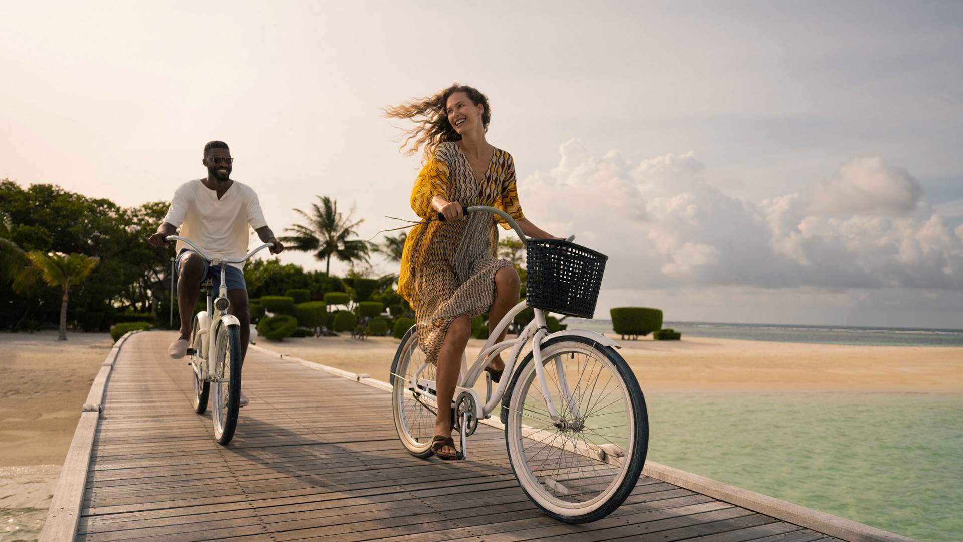 Couple cycling along the deck at LUX* South Ari Atoll
