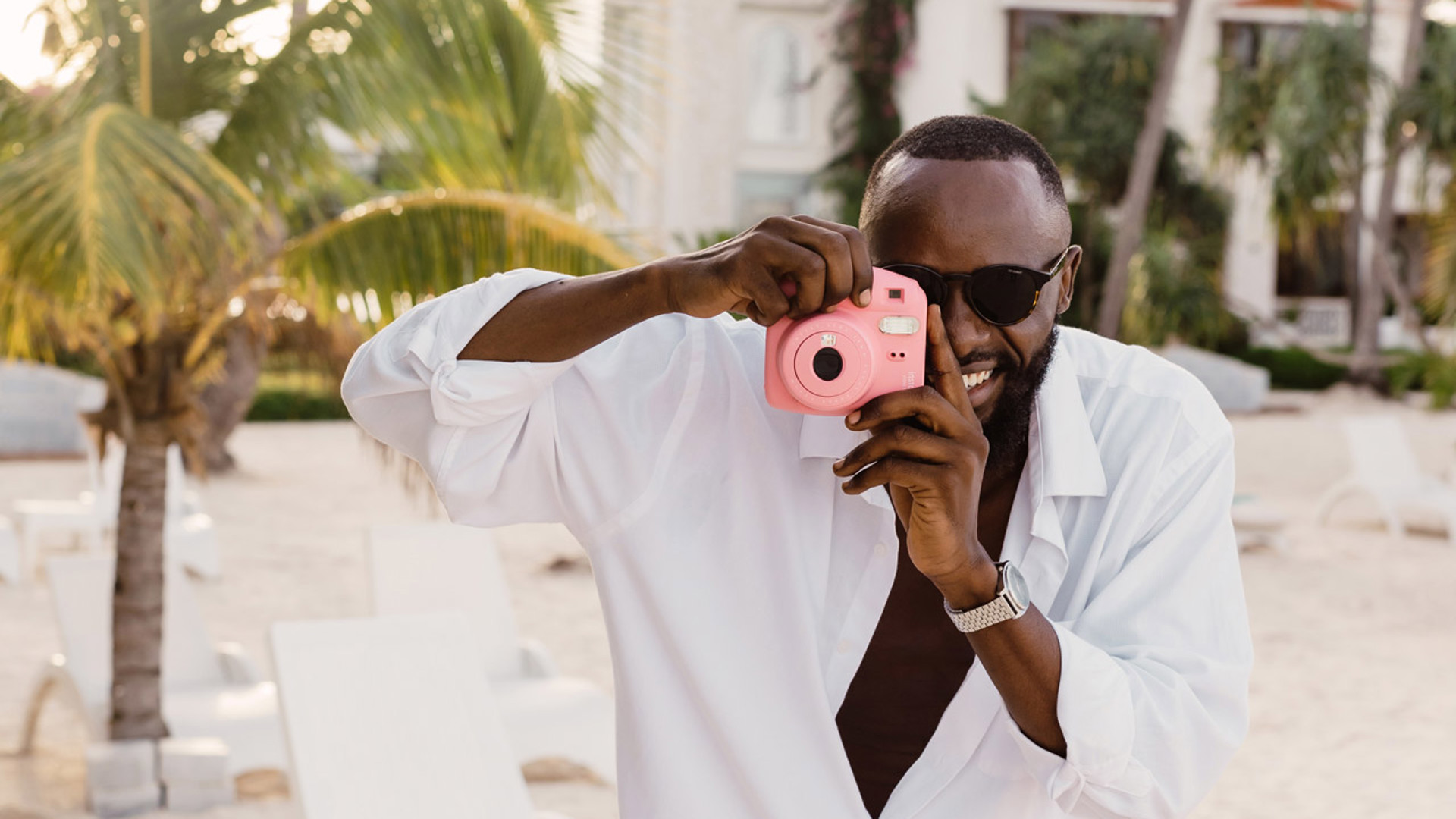 Man taking a picture on the beach of LUX* Marijani